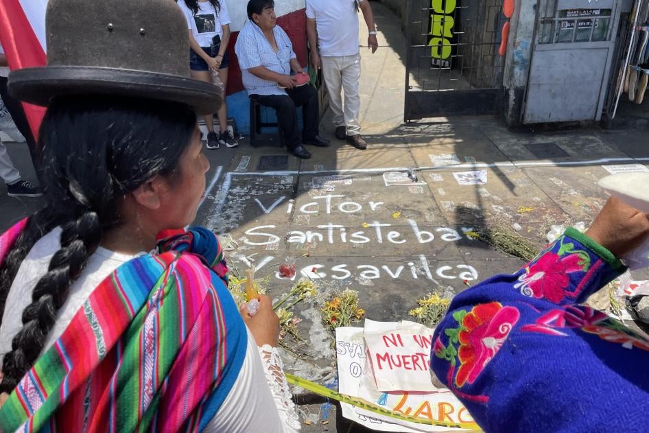 An Indigenous woman looks at a memorial to Víctor Santisteban Yacsavilca