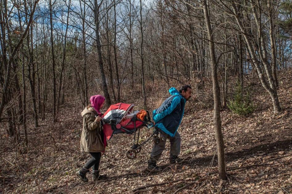 A man and his daughter carry a baby in a stroller through a forest