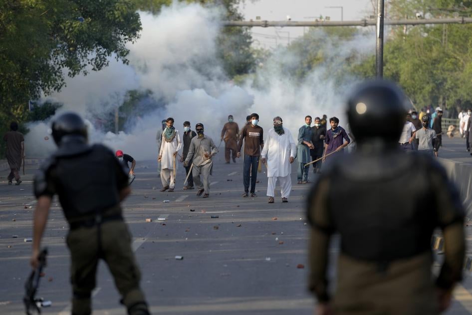 Supporters of Pakistan's former Prime Minister Imran Khan throw stones after police fire tear gas to disperse them protesting against the arrest of Khan in Lahore, Pakistan.
