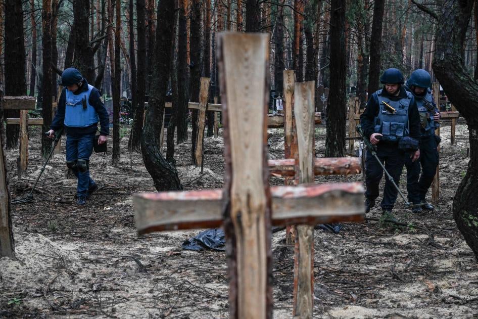 Ukrainian military personnel search for land mines at a burial site in a forest on the outskirts of Izium, eastern Ukraine, September 16, 2022. 