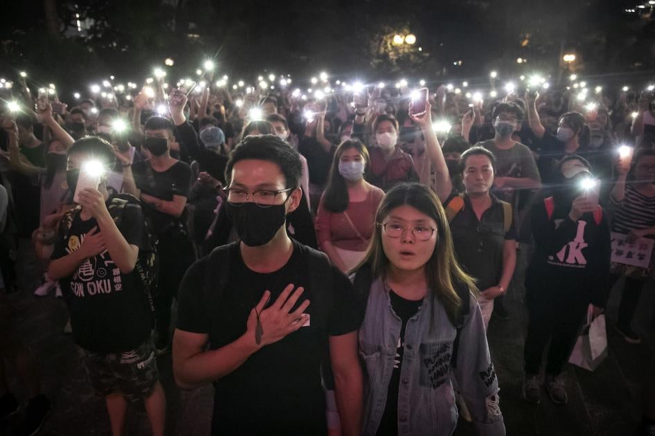 Photo of a crowd singing at a rally taken at night 