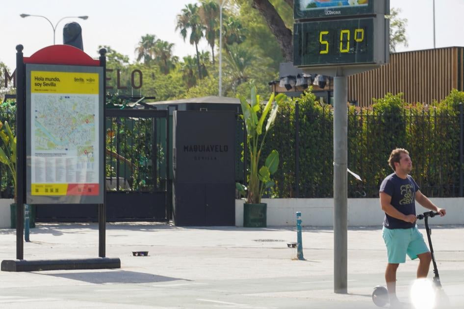 Un cartel en el Paseo de las Delicias, Sevilla (Andalucía, España), el 25 de julio de 2022, que muestra una temperatura elevada de 50 grados Celsius, y un hombre en patineta.