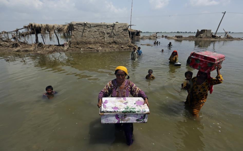 Women carry belongings salvaged from their flooded homes after monsoon rains in the Qambar Shahdadkot district of Sindh province, Pakistan, September 6, 2022.