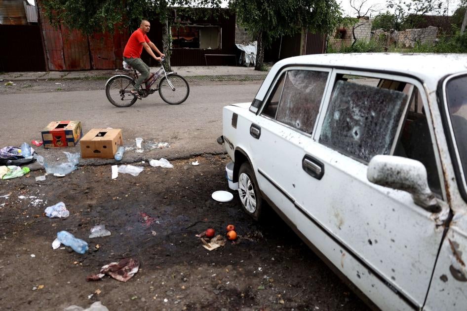Un homme passe à vélo devant l'endroit où une femme a été tuée par une frappe d'arme à sous-munitions russe à Lyman, dans la région de Donetsk en Ukraine, le 8 juillet 2023. 