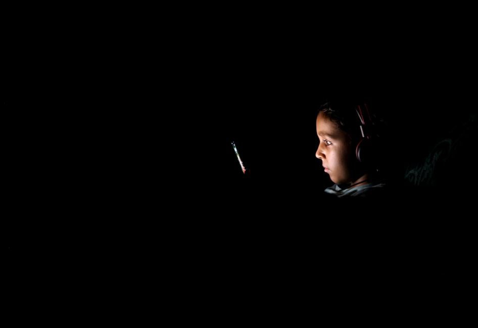 طفلة تنظر إلى شاشة هاتفها الخلوي خلال إحدى فترات تخفيض الأحمال المخطط لها والتي أطلقتها الحكومة لمواجهة الضغط على الطلب على الكهرباء بسبب الاستهلاك المتزايد وسط موجة الحر في القاهرة، مصر في 23 يوليو/تموز 2023. 