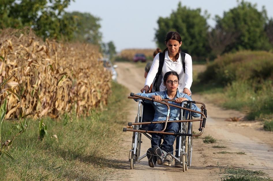 Nujeen, qui se déplace en fauteuil roulant, et sa sœur empruntent un chemin de terre après avoir fui leur Syrie natale. 