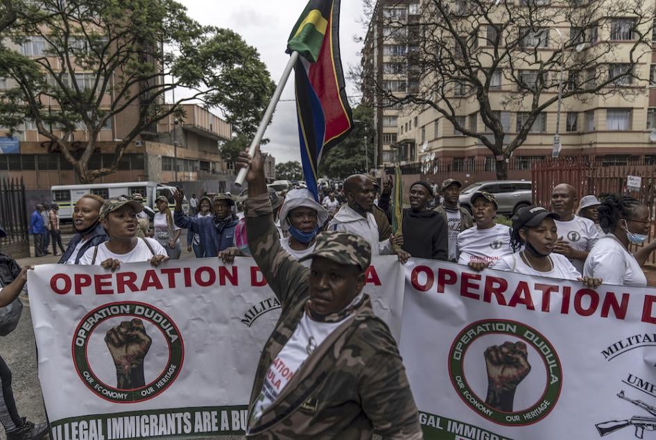 A man holds up a South African flag as members of "Operation Dudula" march down a street in the Hillbrow neighborhood to deliver memoranda to several businesses in the area, Johannesburg, South Africa, February 19, 2022. 