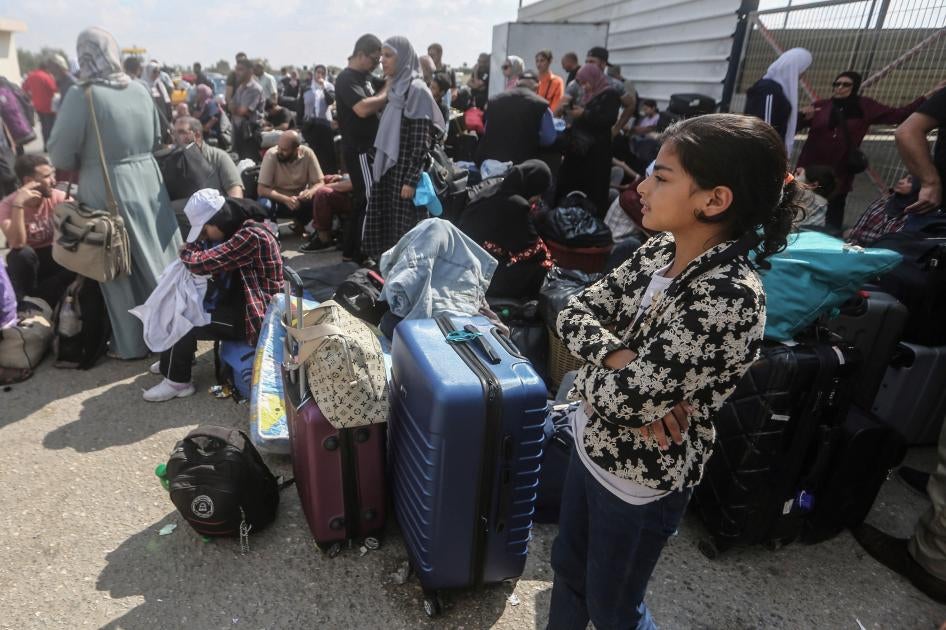 People wait with their belongings near the border
