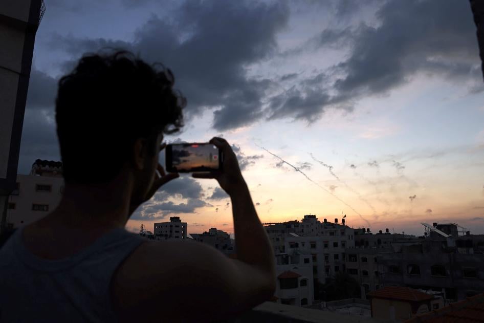 Seorang pria merekam video dengan ponselnya tentang roket-roket yang ditembakkan dari Kota Gaza ke Israel pada 7 Oktober 2023.