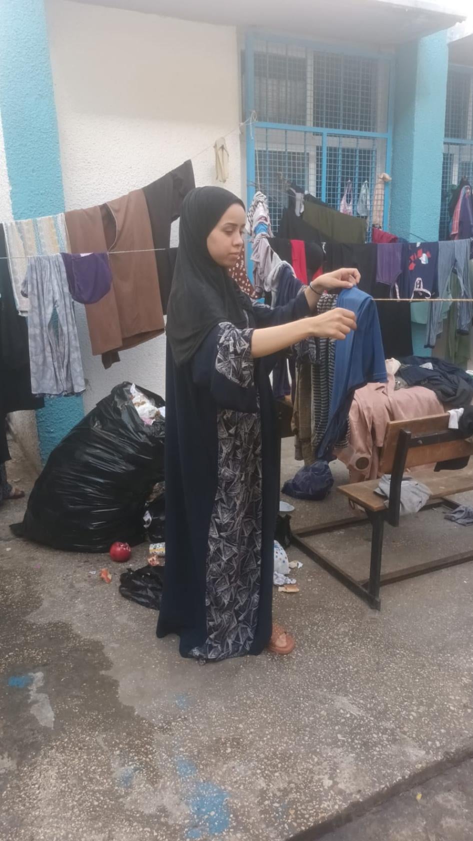 Iman, une jeune femme palestinienne malentendante, séchait du linge à l’extérieur d’une école dans le sud de la bande de Gaza. Elle s’y est réfugiée en octobre 2023 avec sa sœur Abir, également malentendante, après que leur quartier ait été attaqué par Israël.