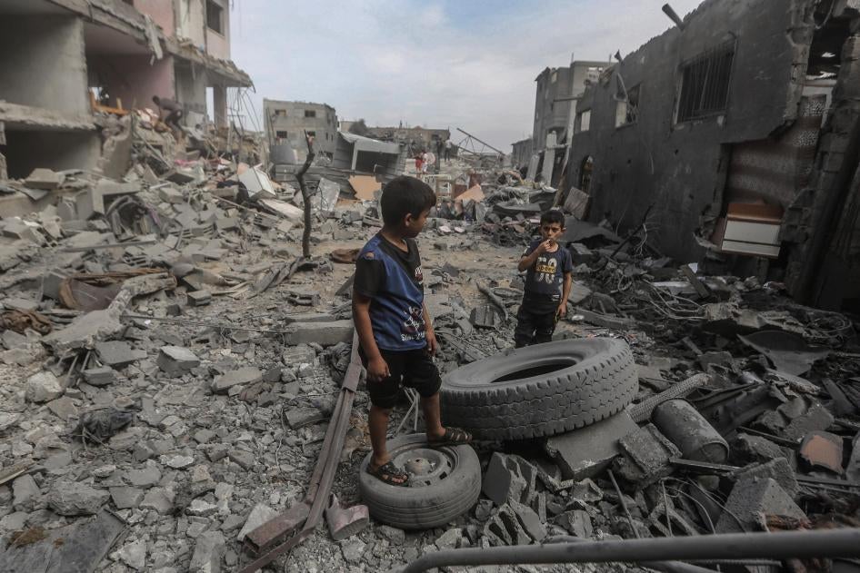 Deux jeunes garçons palestiniens photographiés le 29 octobre 2023 parmi des décombres et pneus dans le camp d'Al-Bureij, situé dans la bande de Gaza et touché par des frappes aériennes israéliennes. 