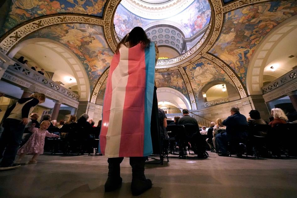 Glenda Starke wears a transgender flag as a counter protest during a rally in favor of a ban on gender-affirming health care legislation, March 20, 2023, at the Missouri Statehouse in Jefferson City. ©2023 AP Photo/Charlie Riedel, File