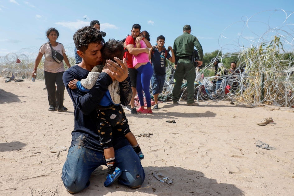 A migrant embraces his son after finishing the long journey to the US from Venezuela, in Eagle Pass, Texas, September 25, 2023. © 2023 Robert Gauthier/Los Angeles Times via Getty Images