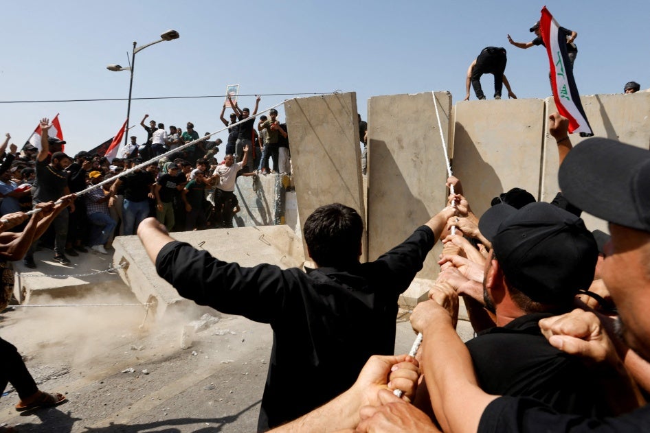 Supporters of Iraqi Shi'ite cleric Moqtada al-Sadr pull down a concrete barrier during a protest against corruption, in Baghdad, Iraq, July 30, 2022.