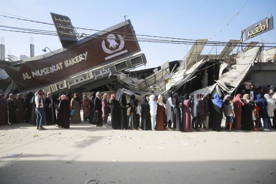 People line up for bread at a partially collapsed but still operational bakehouse in Nuseirat refugee camp in Deir al Balah, Gaza, November 4, 2023. © 2023 Ashraf Amra/Anadolu via Getty Images 