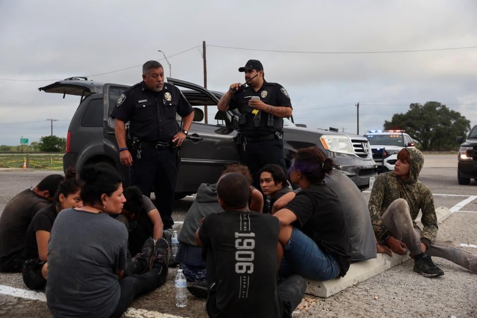 Asylum seekers from Central America sit by the road after police detained them in Hondo, Texas, about 100 miles from the US-Mexico border, June 1, 2022. 