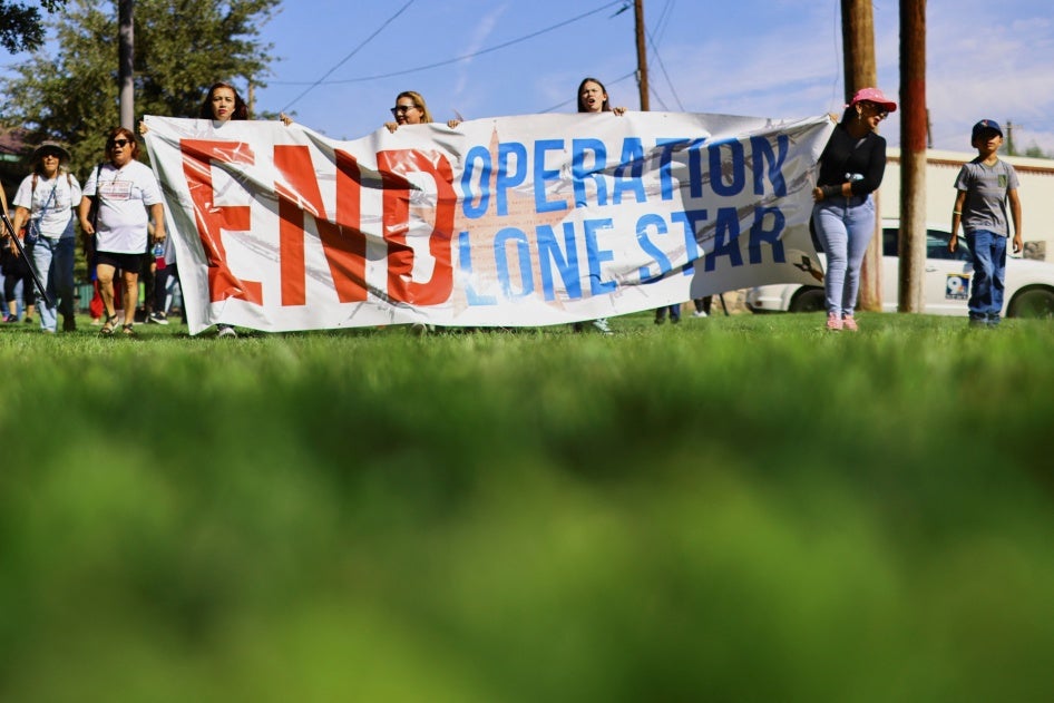 People hold a banner during a protest against Operation Lone Star after members of the Texas National Guard shot and wounded a 22-year-old near the Bridge of the Americas in El Paso, Texas, September 1, 2023. © 2023 REUTERS/Jose Luis Gonzalez