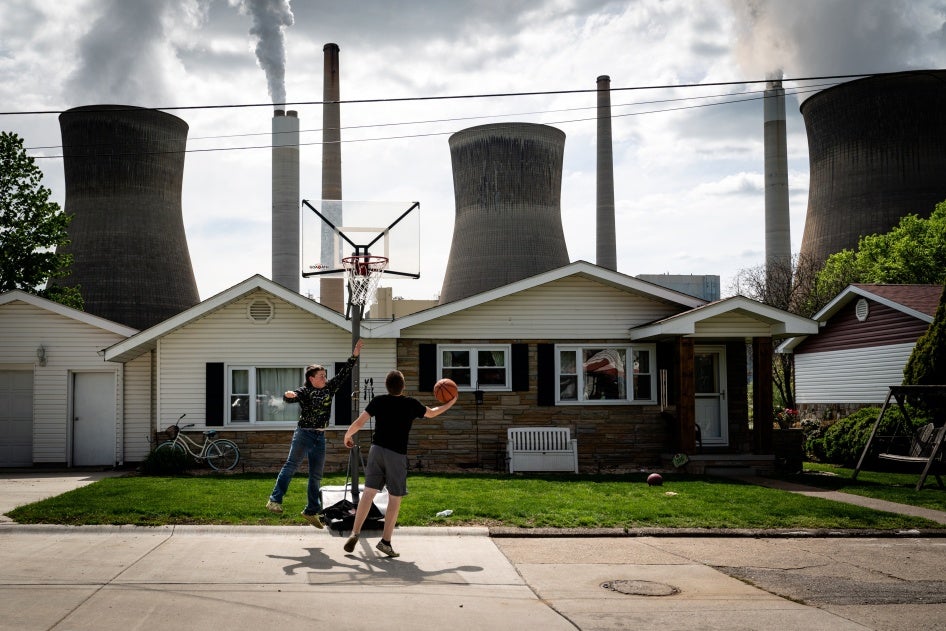 Children play basketball at their home in front of the John Amos coal-fired power plant in Poca, West Virginia, May 6, 2021. 