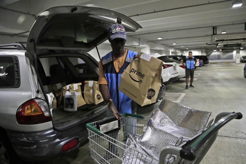 A delivery worker for Amazon Prime, loads his vehicle with groceries from Whole Foods, in Miami, Florida, March 31, 2020.