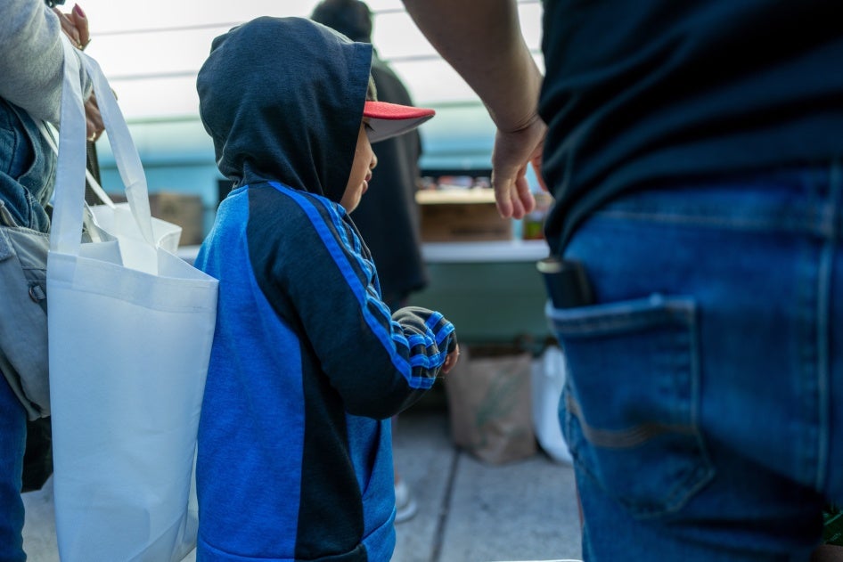 A child joins his father as Bronx residents receive food at the St. Helena Pantry on September 28, 2022 in New York City.