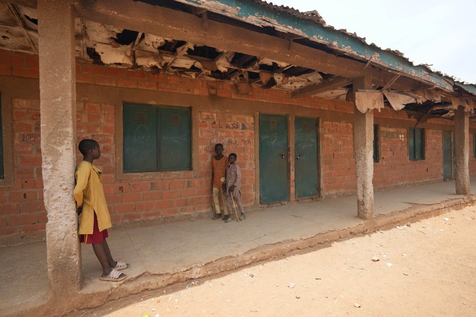 Trois enfants photographiés devant l'école primaire et secondaire LEA de Kuriga (État de Kaduna), dans le nord-ouest du Nigeria, le 9 mars 2024, deux jours après l'enlèvement de 287 élèves qui s’y trouvaient alors.