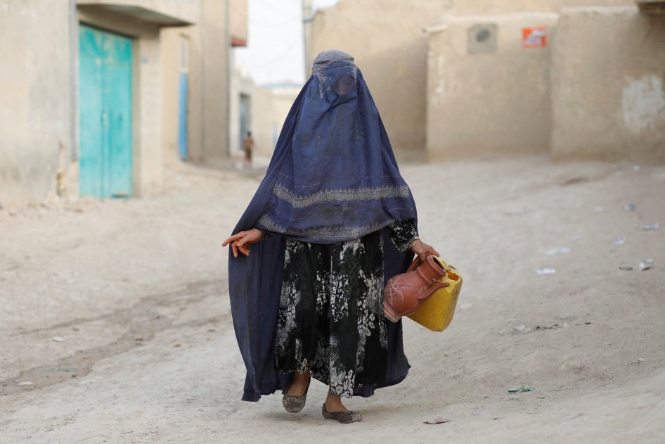 Une femme afghane tenant une cruche et un bidon en plastique vides marchait vers un point de distribution d’eau dans le district de Nahr-e-Shahi (province de Balkh) en Afghanistan, le 6 août 2023. 