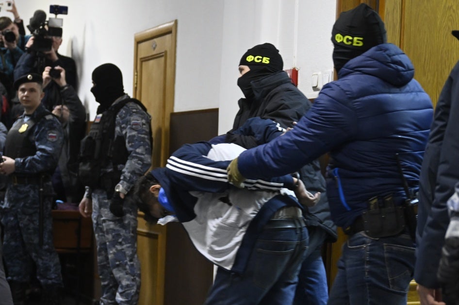 Работники Федеральной службы безопасности ведут Далержона Мирзоева, подозреваемого в совершении теракта в концертном зале «Крокус Сити Холл», в Басманном районном суде города Москвы.