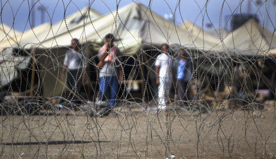 سجناء يقفون إلى جانب خيامهم في سجن أبو غريب إلى الغرب من بغداد، العراق، 15 يوليو/تموز 2004. 