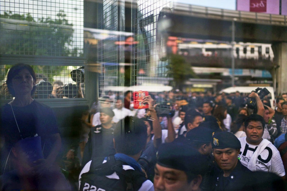 A woman (left) sits inside a police van after being detained by police for holding an anti-coup placard in Bangkok, Thailand, on May 29, 2014.
