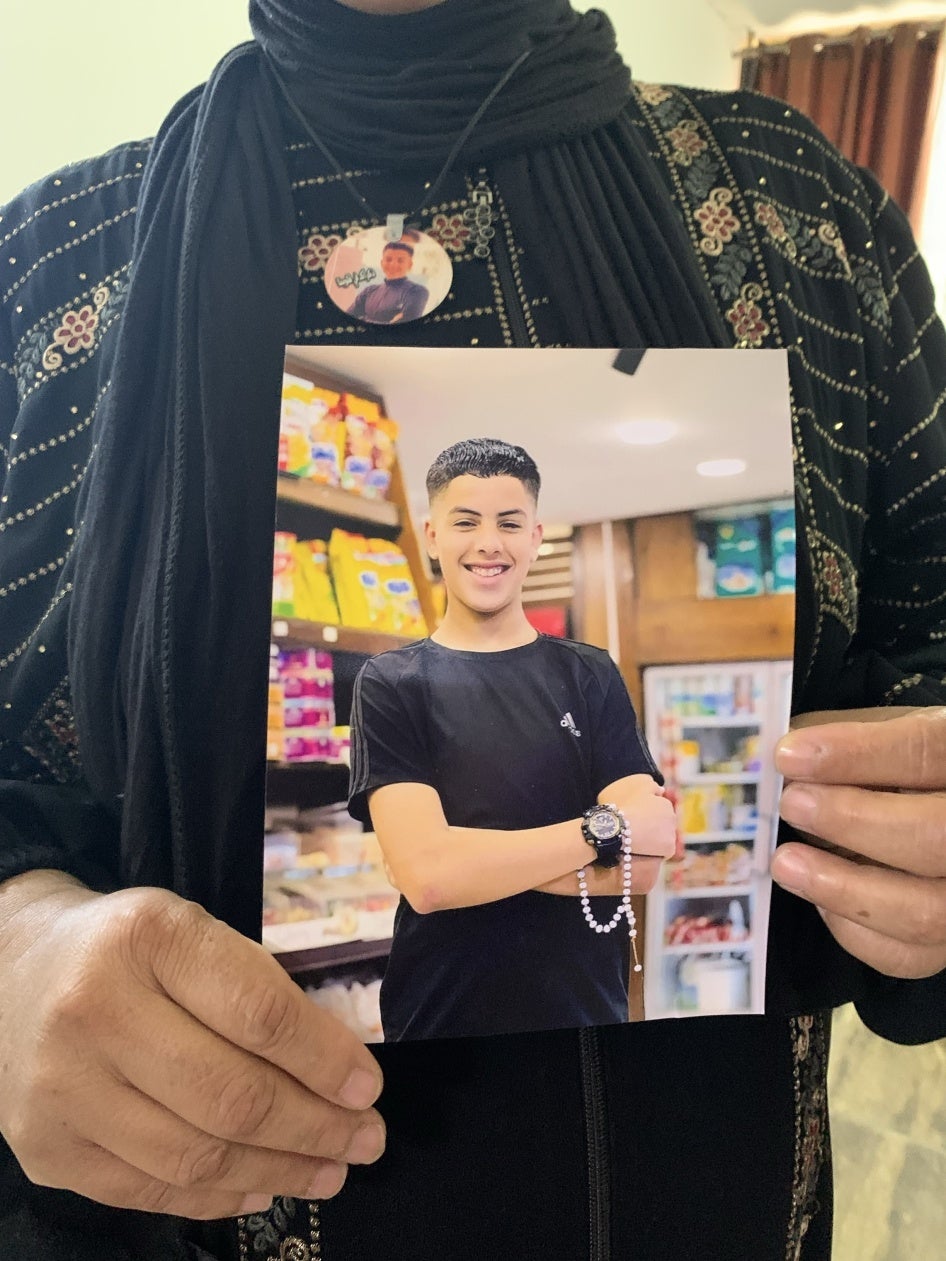 Taha Mahamid's mother holds a photo of her son, whom Israeli forces killed on October 19, 2023 when he was 15, at the Nur Shams Refugee Camp in the occupied West Bank city of Tulkarem, November 2, 2023. 