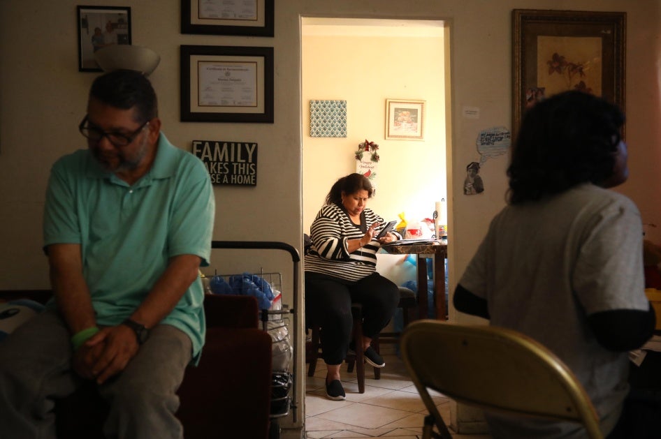 Marisol Coronado, center, prepares for a zoom call, while her husband and son spend time in the living room of their apartment in Huntington Park on April 19, 2024.