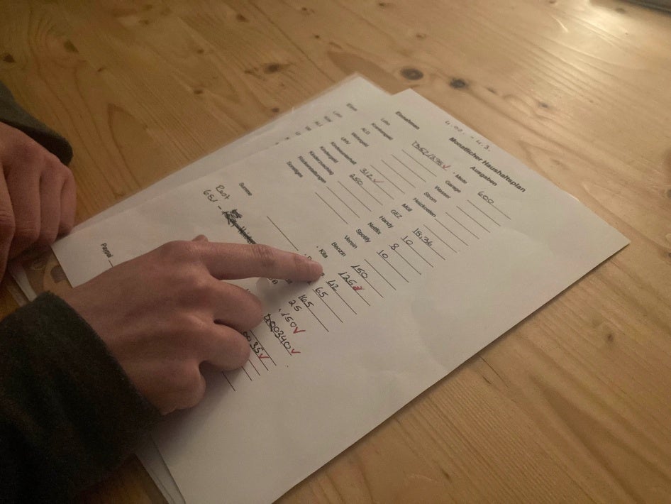 ine alleinerziehende Mutter, die im Niedriglohnsektor arbeitet, zeigt Human Rights Watch ihr monatliches Haushaltsbudget, während eines Interviews, Baden-Württemberg, Februar 2023