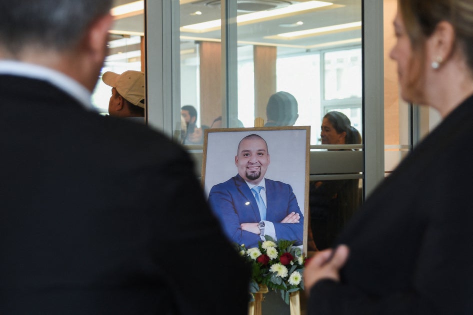 People stand near a framed photo of Guatemalan lawyer and anti-corruption figure Juan Francisco Solorzano Foppa, who died after being shot by unknown assailants on Saturday while visiting a sports center, during his wake at a funeral home in Guatemala City, Guatemala, October 19, 2026.