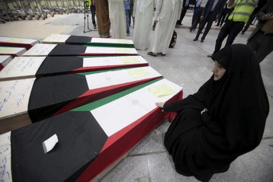 A woman grieves next to the coffins of victims of the bombing at the Imam Sadiq Mosque mosque in Kuwait City, at the international airport in Najaf, south of Baghdad, June 27, 2015.