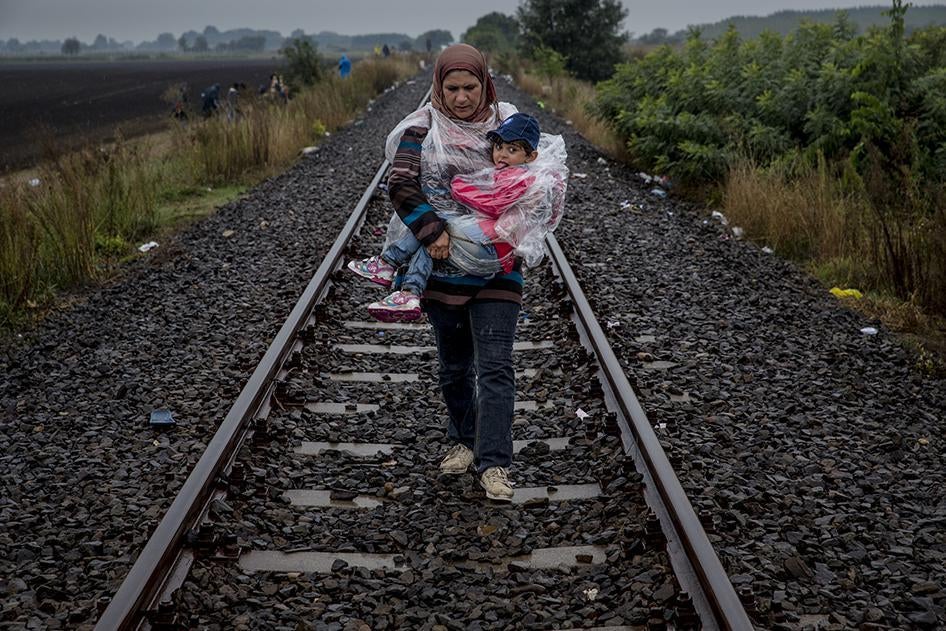 Seorang perempuan menggendong anaknya sepanjang jalur rel kereta setelah menyeberangi perbatasan Hungaria dari Serbia, menuju titik kumpul Roszke tempat mereka akan menumpang bus ke sebuah kamp penampungan sementara. 10 September 2015. 