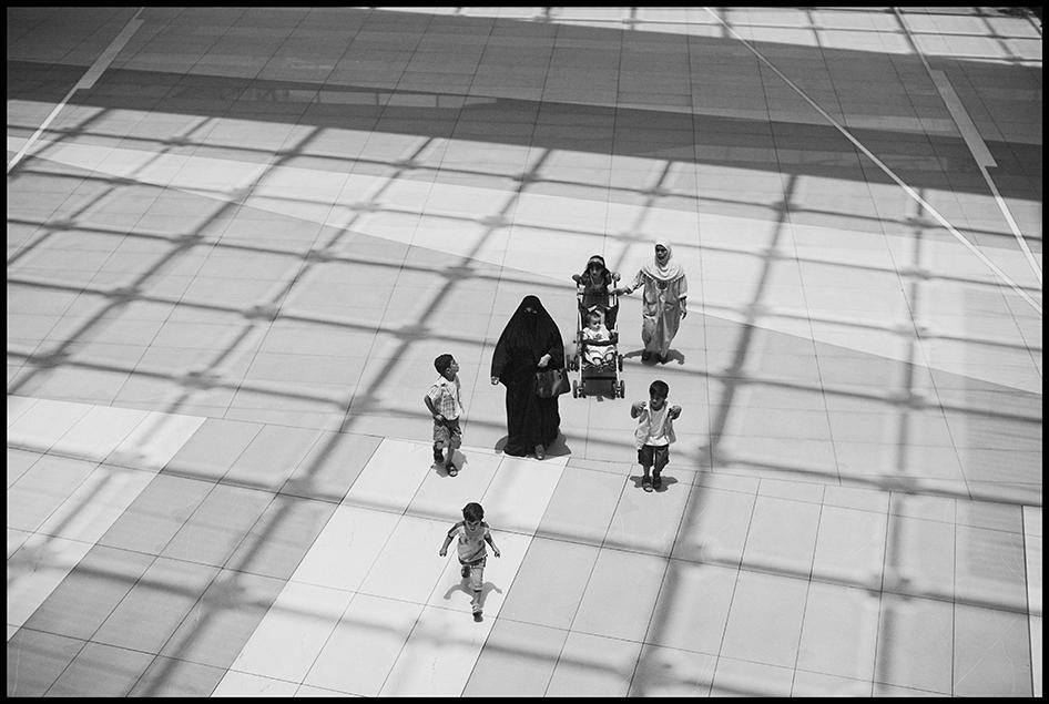 صاحبة عمل وأطفالها ومعهم عاملة منزلية، في الخلف على اليمين، يسيرون في مركز "الأفنيوز" التجاري الفاخر في مدينة الكويت.