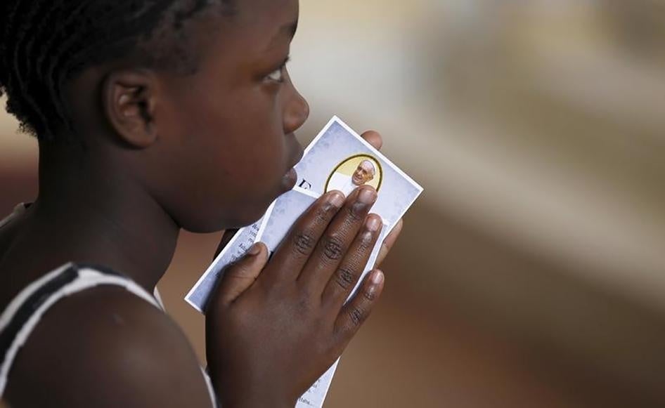 A child holds a prayer paper with the photo of Pope Francis during a special mass at St. Joseph the Worker Catholic Parish within Kangemi, a slum that is home to 650,000 people in Kenya's capital Nairobi, on November 22, 2015. 