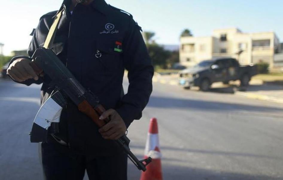 Un membre des forces de sécurité libyennes, l’arme au poing, surveille la circulation sur une route menant à un poste de police à Benghazi, le 4 décembre 2014. 