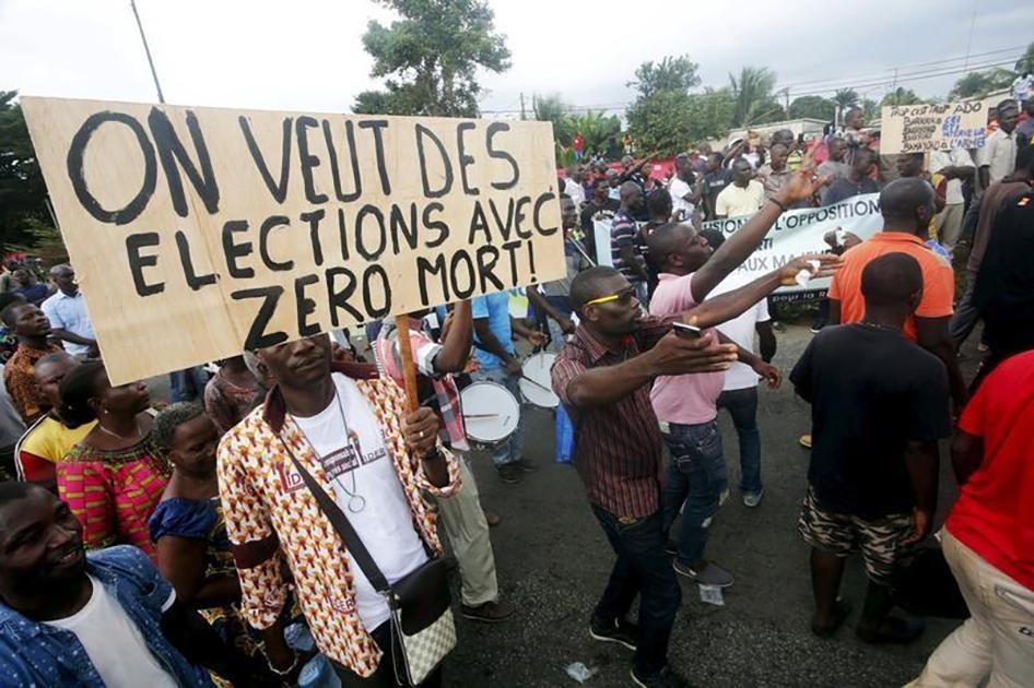 Members of the opposition National Coalition for Change hold a sign reading "We want election with zero dead" as they chant slogans during a protest march in Abidjan, Côte d’Ivoire on September 28, 2015