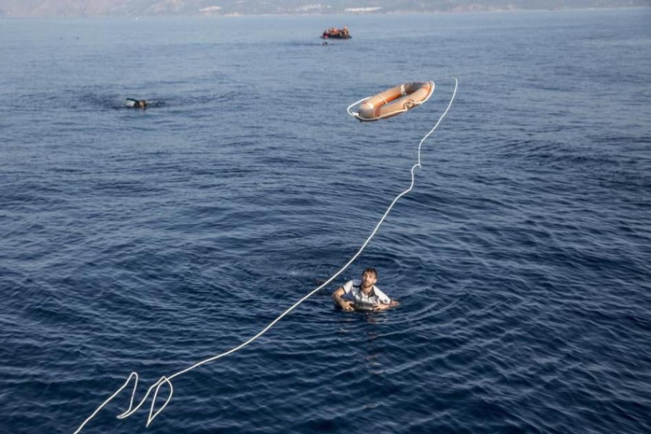 Members of the Hellenic Coast Guard on a rescue mission throw a life preserver ring to a man in distress in the sea near the Greek island of Lesbos, after he jumped from a sinking rubber dingy.  