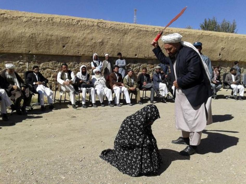 An Afghan judge hits a woman with a whip in front of a crowd in Ghor province, Afghanistan August 31, 2015.