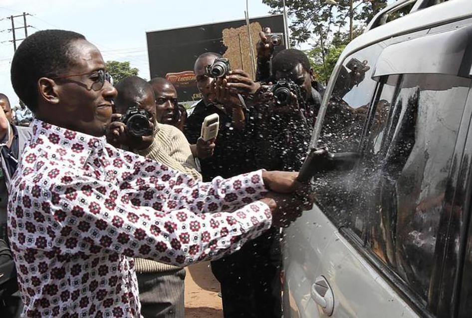 A Ugandan security officer uses a pistol to break the window of a car which Forum for Democratic Change (FDC) leader Kizza Besigye is in, as he is prevented from circulating in Uganda's capital Kampala on April 28, 2011. Besigye was eventually pepper-spra