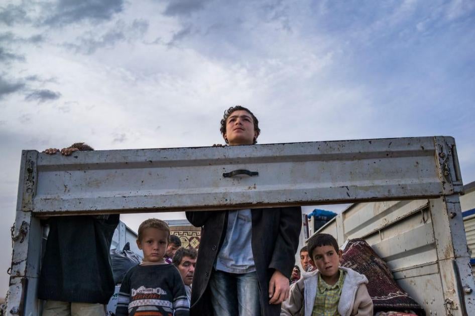 Сирийские беженцы курдского происхождения выглядывают из грузовика по пути в Турцию из сирийского города Кобани (Айн-эль-Араб) и его окрестностей. Сентябрь 2014 г.