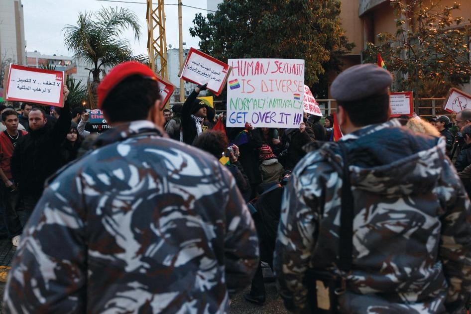 In this Sunday, Feb. 22, 2009 picture, Lebanese police stand guard as protesters carry banners during a sit-in for gays and lesbians in Beirut. 