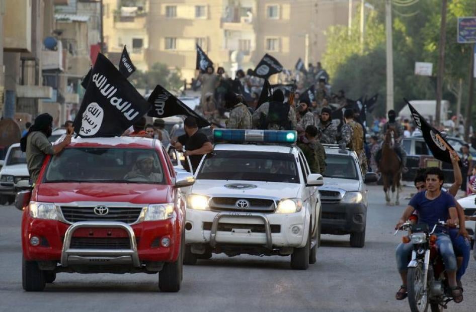 Militant Islamist fighters waving flags, travel in vehicles as they take part in a military parade along the streets of Syria's northern Raqqa province, June 30, 2014. 