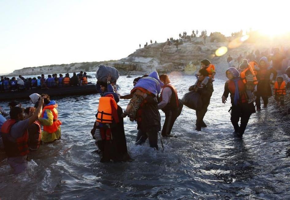 Refugees carrying their children walk towards a dinghy to sail off for the Greek island of Chios from Cesme, Turkey November 4, 2015. 