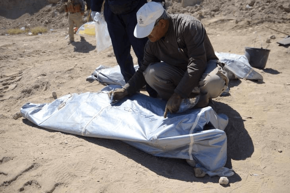 A member from the Iraqi forensic team writes on the body bag of remains belonging to Shi'ite soldiers from Camp Speicher who have been killed by Islamic State militants at a mass grave in the presidential compound of the former Iraqi president Saddam Huss