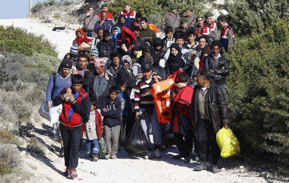 Turkish Gendarmes lead a group of refugees to buses to prevent them from sailing off for the Greek island of Chios by dinghies, at a beach in the western Turkish coastal town of Cesme.