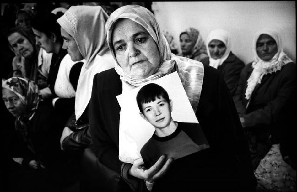 一名妇女抱着失踪儿子的照片，她和其他波斯尼亚穆斯林做为斯雷布雷尼察（Srebrenica）屠杀的死难者家属及幸存者与荷兰前维和部队见面。