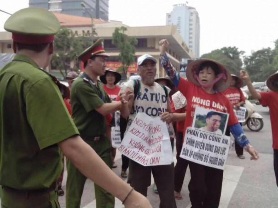 靳氏絩（Can Thi Theu）持著儿子郑伯秀（Trinh Ba Tu）的照片抗议警察暴力，他在2015年6月遭亲政府流氓攻击。